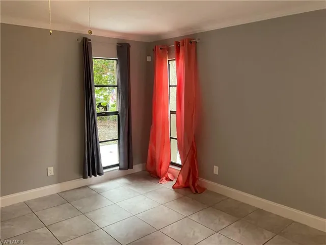 Tiled empty room with plenty of natural light and crown molding