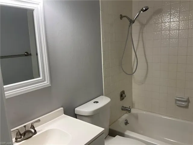 Full bathroom with tiled shower / bath combo, vanity, and toilet