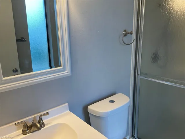 Bathroom featuring walk in shower, sink, and toilet