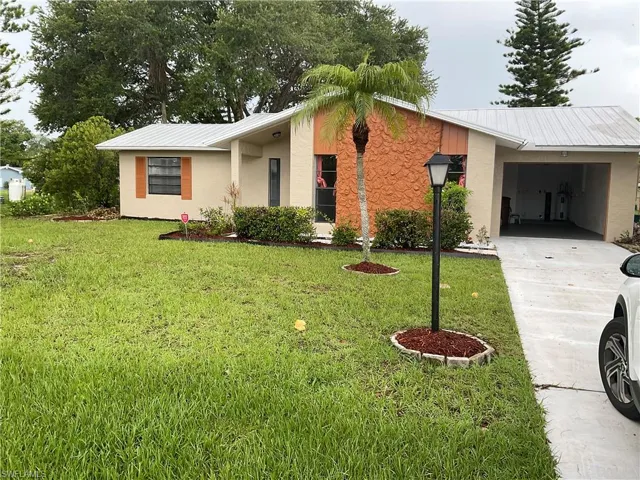 Ranch-style house featuring a front yard and a carport