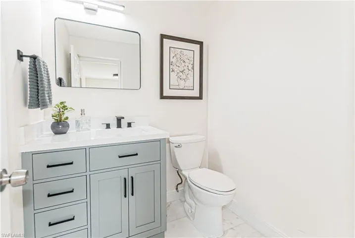 Vanity featuring a light blue cabinet with matte black hardware, a white countertop with an integrated sink, and a rectangular mirror with a modern light fixture
