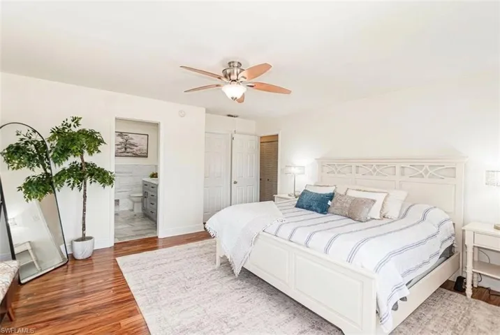 Bedroom featuring wood-finish flooring, a white paneled headboard, and a ceiling fan with integrated lighting