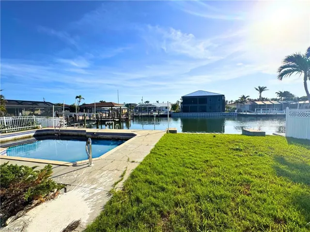 View of dock with a lawn, a water view, fence, and boat lift  - Virtually Edited Image