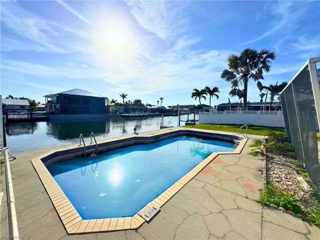 View of pool featuring a water view, fence, and a fenced in pool  - Virtually Edited Image
