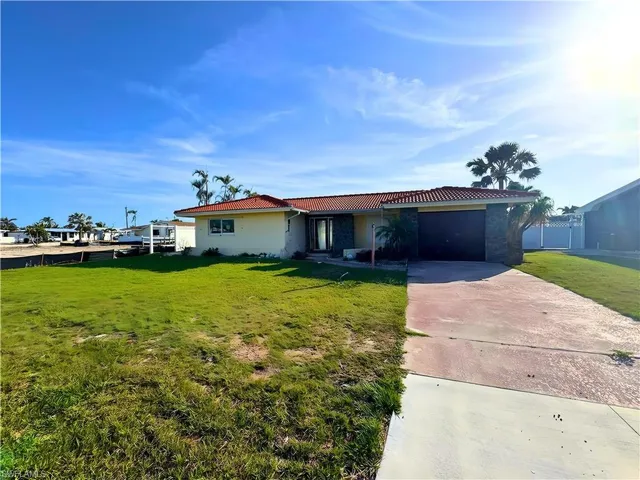 Ranch-style home featuring a tile roof, concrete driveway, stucco siding, a front lawn, and a garage  - Virtually Edited Image