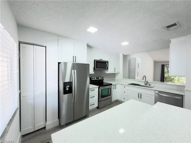 Modern kitchen featuring white cabinetry, stainless steel appliances, light countertops, and recessed lighting