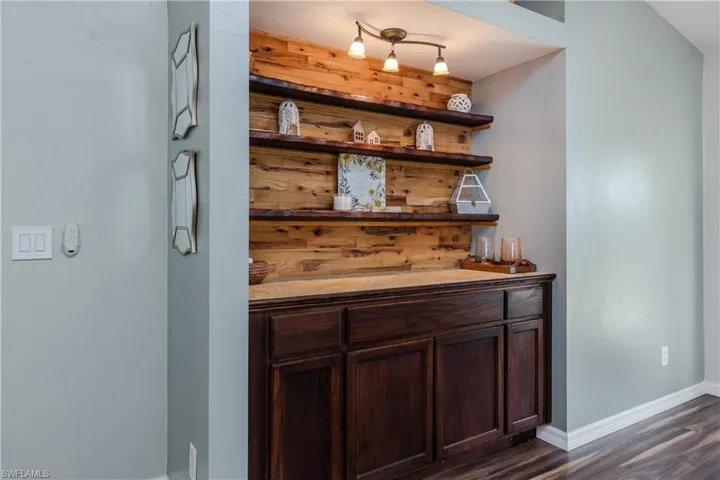 Bar featuring open shelves, dark brown cabinets, and dark wood-style floors