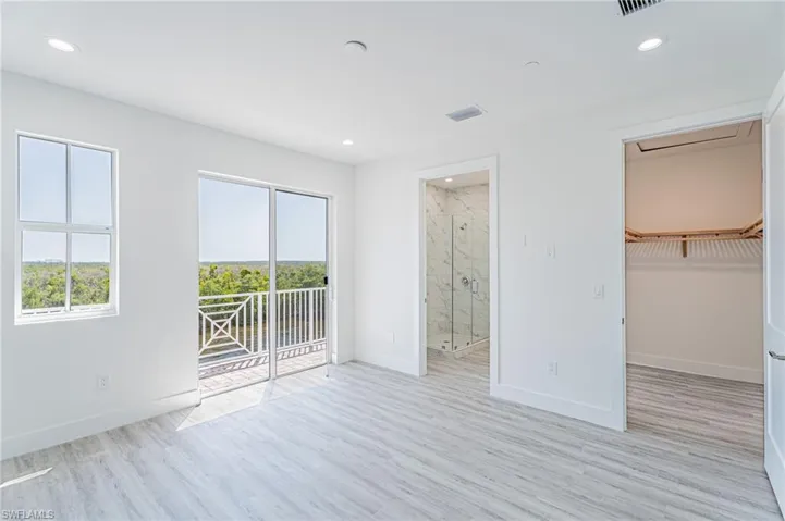 Unfurnished bedroom with access to exterior, a walk in closet, light wood-type flooring, and recessed lighting