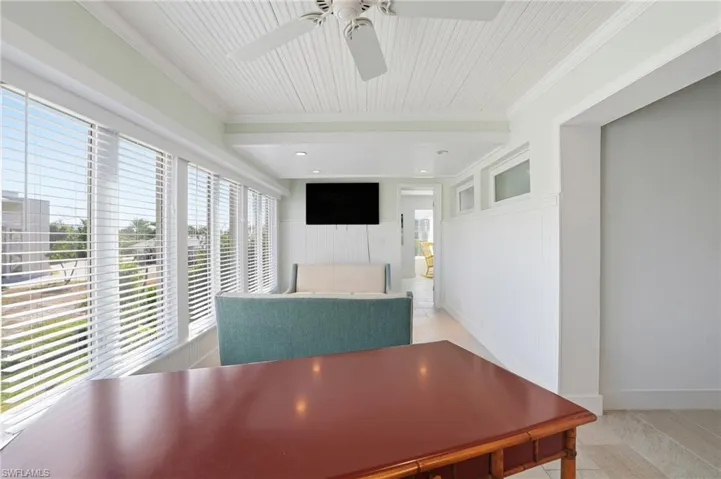 Dining room featuring light tile patterned floors, ornamental molding, a wainscoted wall, and ceiling fan - Virtually Edited Image