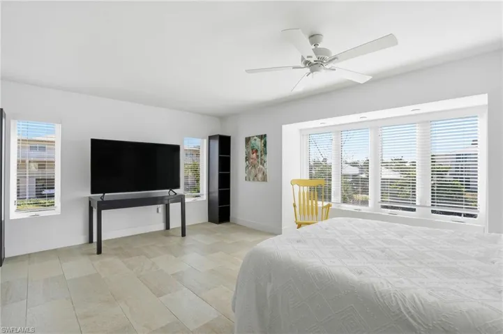 Bedroom featuring multiple windows and a ceiling fan - Virtually Edited Image