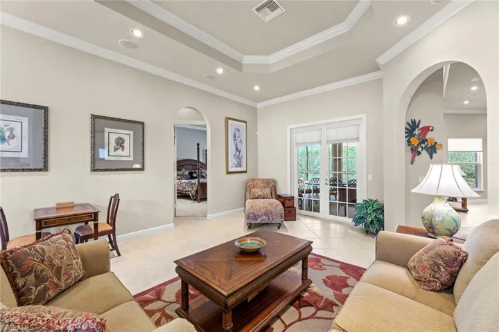 Tiled living room with a tray ceiling, french doors, and crown molding