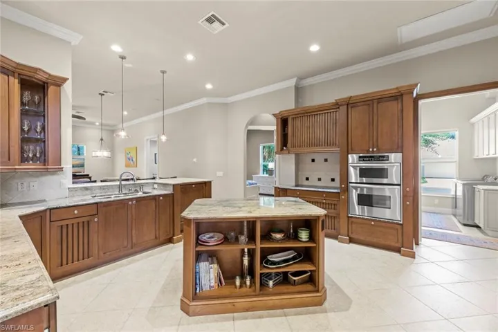 Kitchen with a kitchen island, backsplash, hanging light fixtures, sink, and stainless steel double oven
