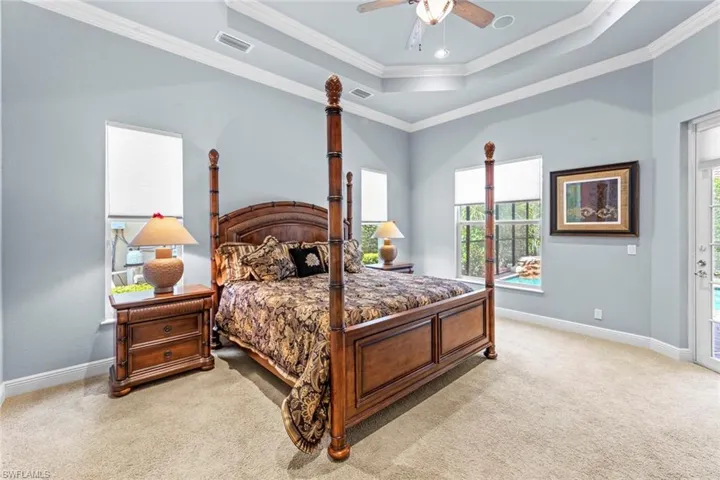 Bedroom featuring ceiling fan, a tray ceiling, crown molding, and light colored carpet