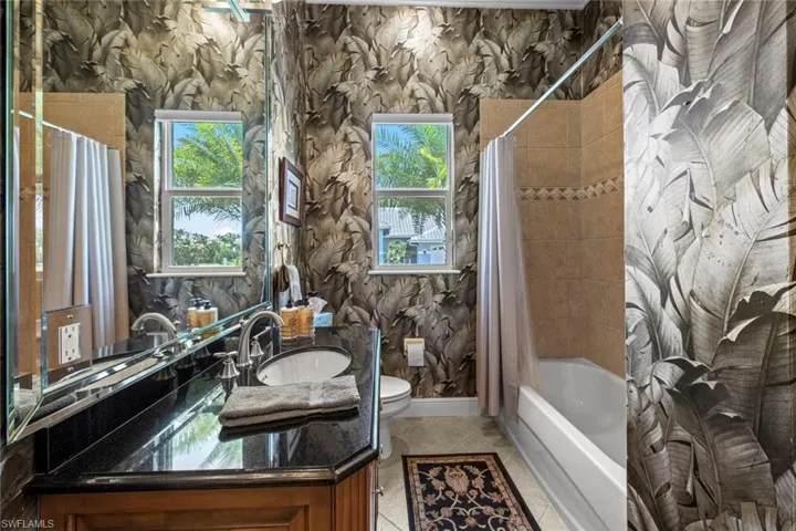 Full bathroom with tile flooring, shower / tub combo, plenty of natural light, and toilet