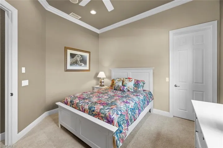 Carpeted bedroom with ceiling fan and crown molding