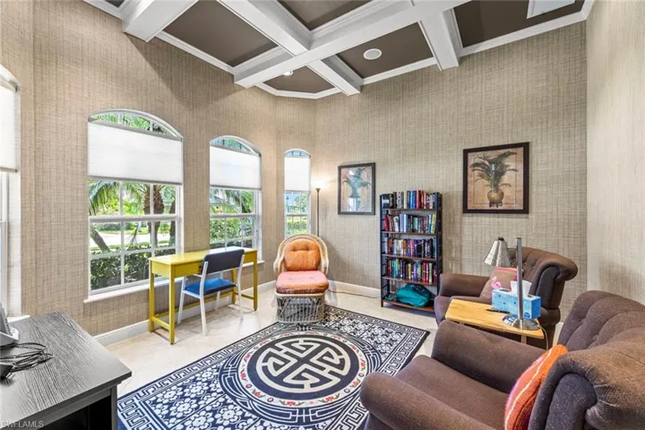 Living room with a towering ceiling, coffered ceiling, crown molding, beamed ceiling, and light tile floors