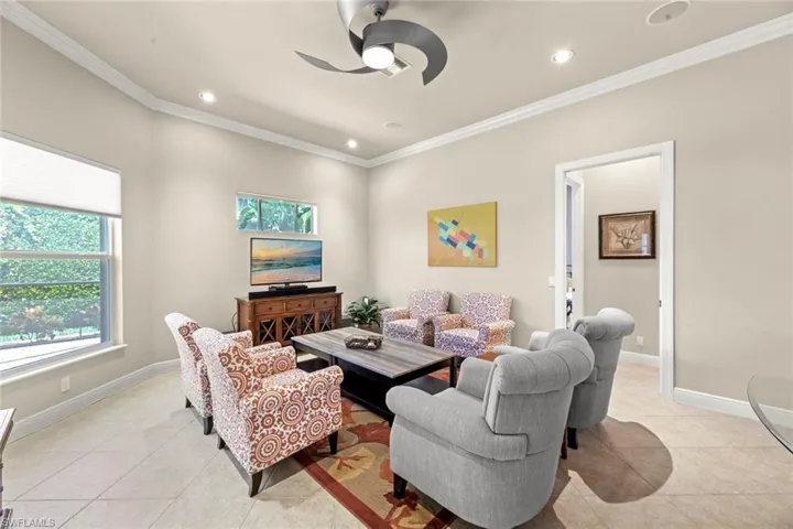 Living room featuring ornamental molding, ceiling fan, and light tile floors