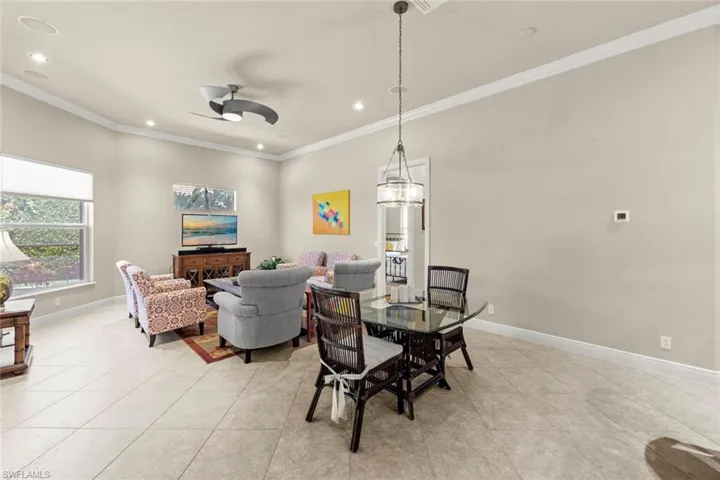 Tiled dining space with ceiling fan and crown molding