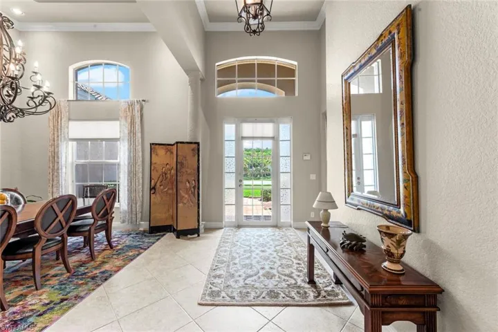 Entrance foyer featuring an inviting chandelier, a towering ceiling, ornamental molding, and tile floors