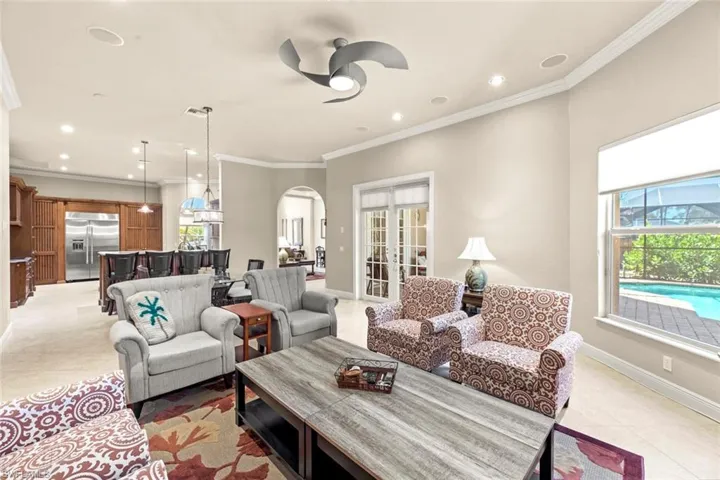 Tiled living room featuring french doors, ornamental molding, and ceiling fan