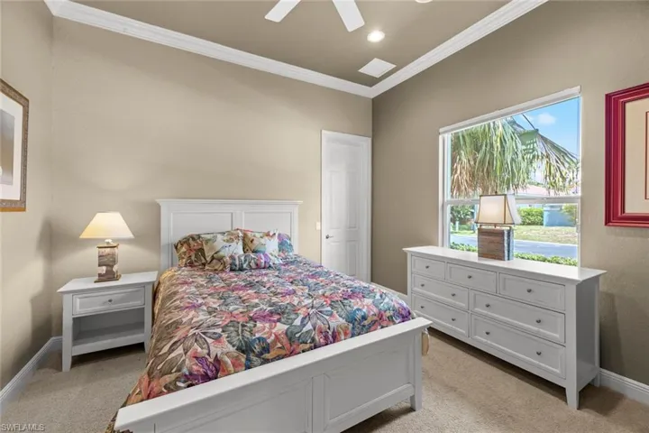 Bedroom with ceiling fan, crown molding, and light colored carpet