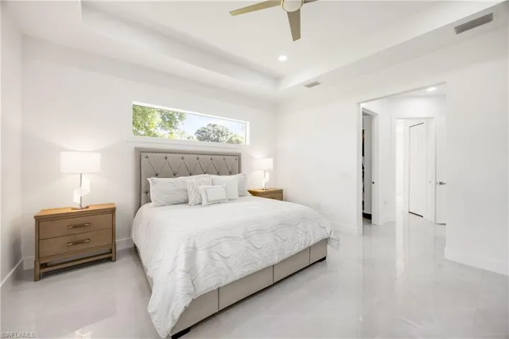Bedroom with a tray ceiling, a ceiling fan, and recessed lighting