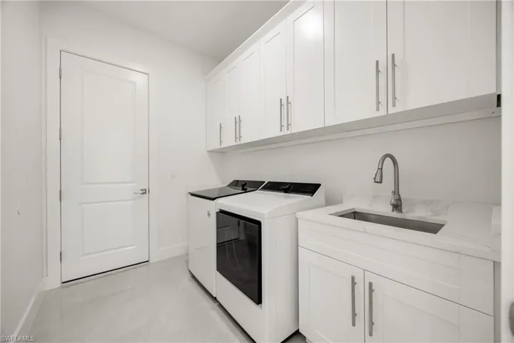 Laundry room featuring cabinet space, washer and clothes dryer, and light tile patterned flooring