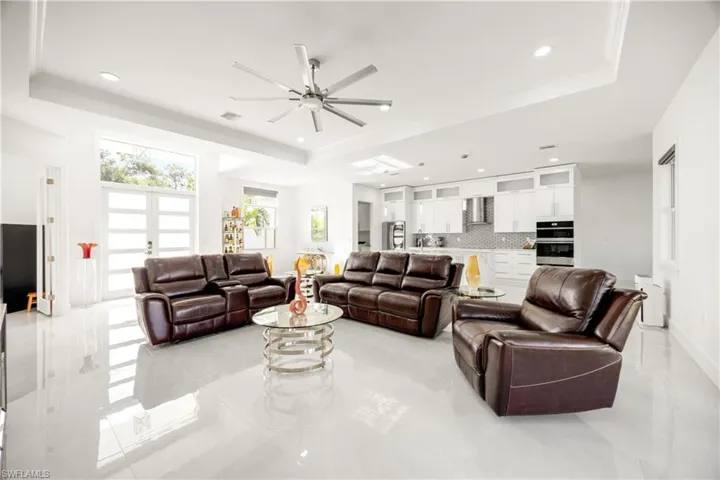 Living area featuring ceiling fan, a tray ceiling, and recessed lighting