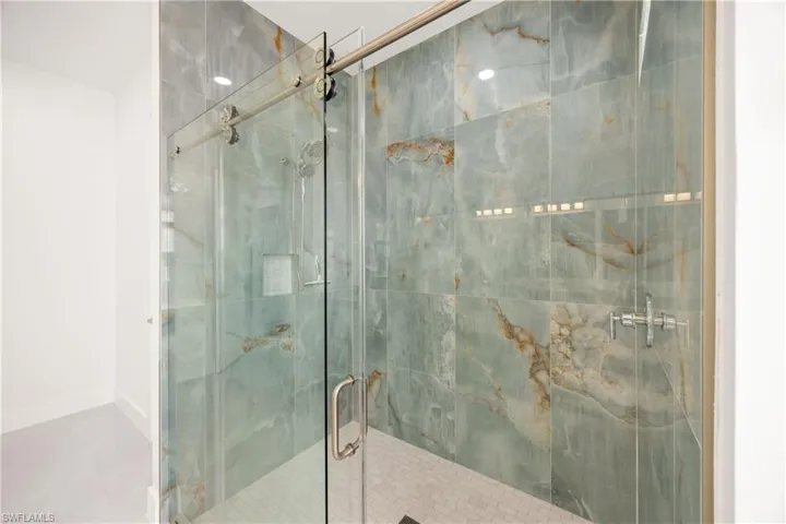 Bathroom featuring a marble finish shower and baseboards