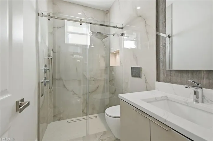 Bathroom featuring a marble finish shower, vanity, and marble tiled floors
