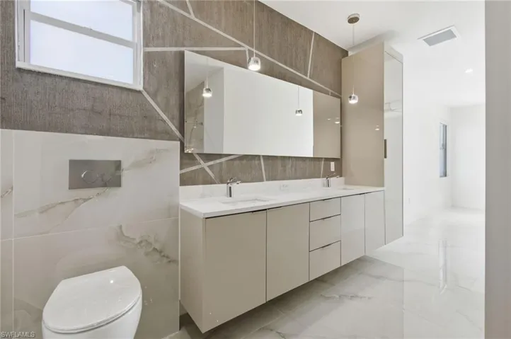 Bathroom with double vanity and light marble finish floors