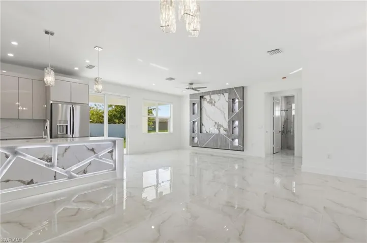 Unfurnished living room with a chandelier, light marble finish floors, recessed lighting, and a ceiling fan