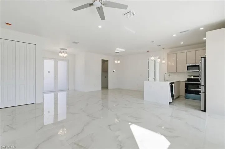 Unfurnished living room with a chandelier, light marble finish flooring, recessed lighting, french doors, and ceiling fan