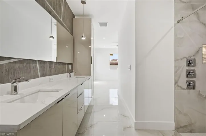 Full bath featuring light marble finish floors, double vanity, and a marble finish shower
