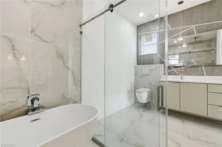 Bathroom featuring a soaking tub, light marble finish flooring, vanity, and a marble finish shower