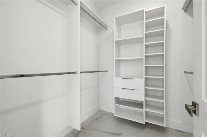 Spacious closet featuring light marble finish floors