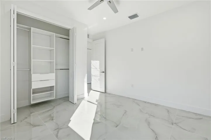 Unfurnished bedroom featuring light marble finish floors, ceiling fan, a closet, and recessed lighting