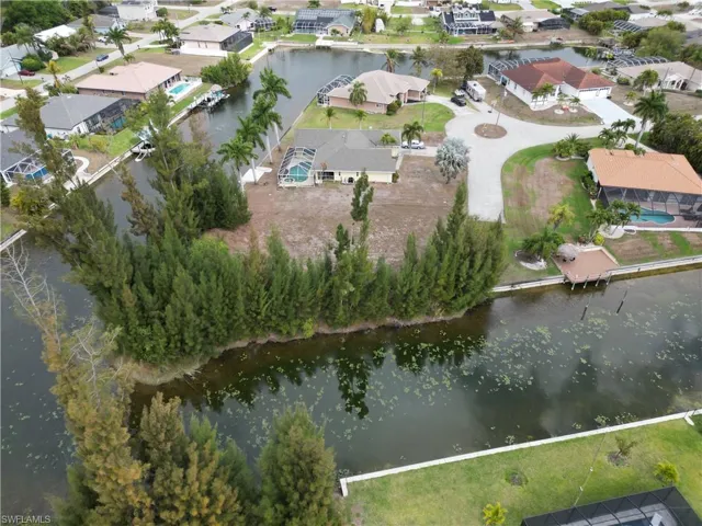 Waterfront property featuring a private boat dock, adjacent canal access, and a screened swimming pool enclosure