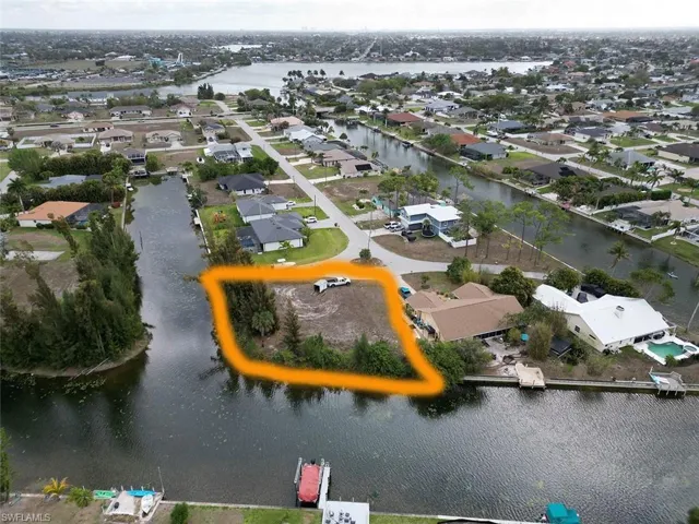 Aerial view of property and surrounding area with property boundaries highlighted, nearby suburban area, and a large body of water
