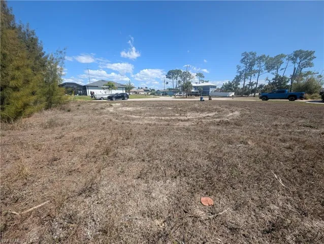 Spacious cleared lot featuring sparse ground cover and a clear sky overhead