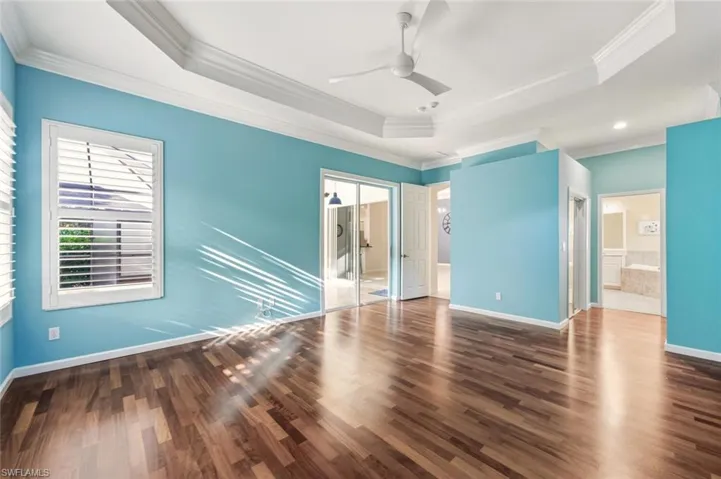 Unfurnished bedroom with a closet, dark wood-type flooring, a ceiling fan, crown molding, and ensuite bathroom