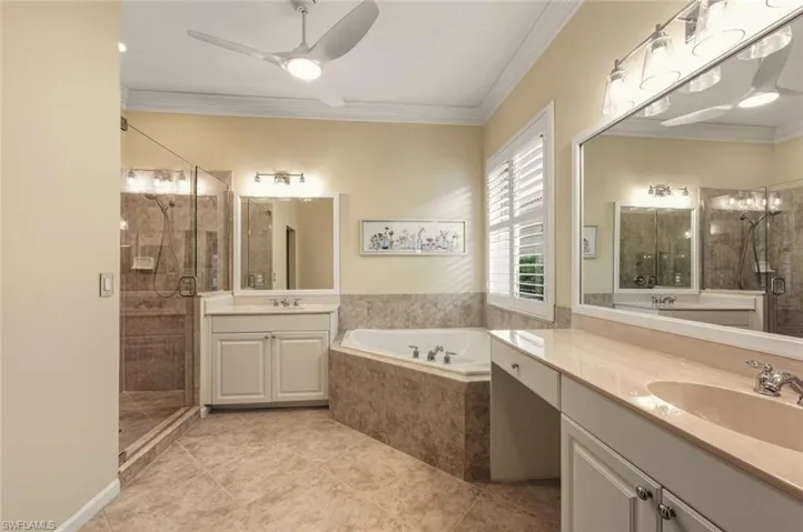 Full bath with a shower stall, crown molding, a bath, two vanities, and ceiling fan