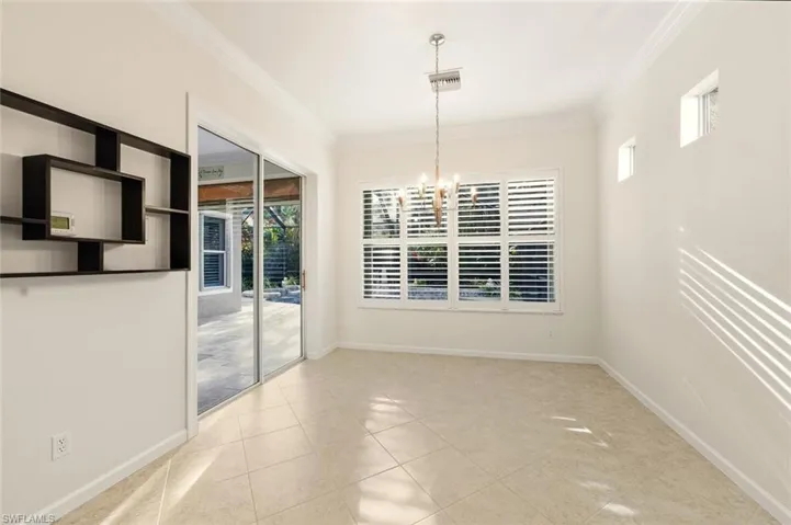 Unfurnished dining area featuring a chandelier, crown molding, and light tile patterned floors