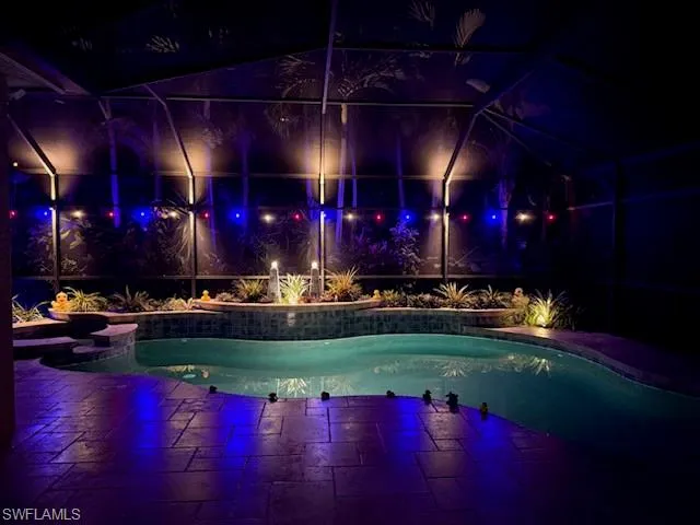 Pool at twilight featuring a lanai, an outdoor pool, and a sunroom