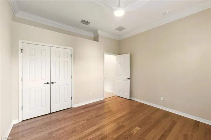 Unfurnished bedroom with ornamental molding, wood finished floors, a ceiling fan, and a closet
