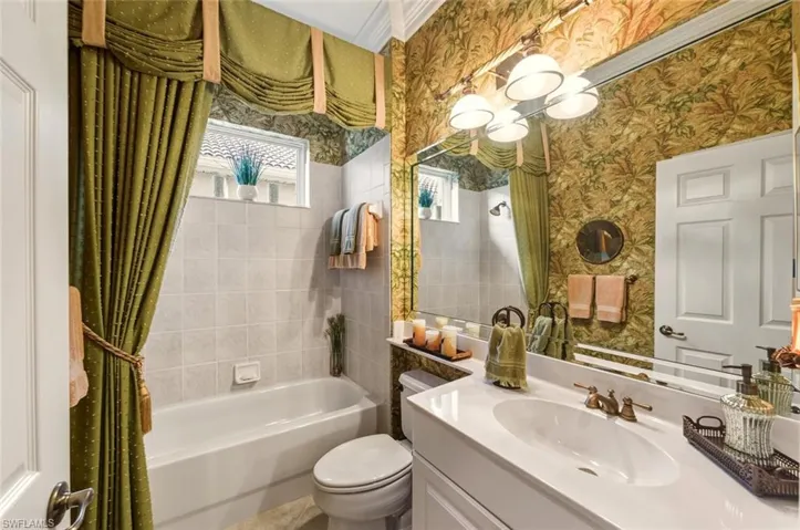 Bathroom featuring vanity, wallpapered walls, and shower / bath combo
