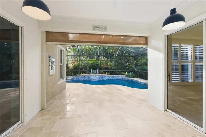 Swimming pool featuring a sunroom, a patio area, and glass enclosure