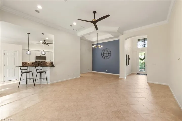 Unfurnished living room with ceiling fan, a chandelier, ornamental molding, recessed lighting, and light tile patterned floors