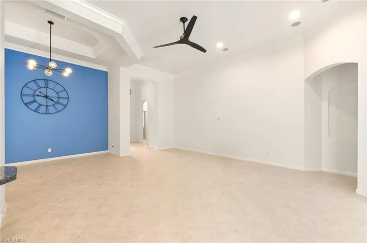 Unfurnished living room with arched walkways, ornamental molding, a ceiling fan, and recessed lighting
