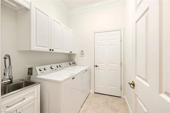 Laundry area with cabinet space, crown molding, and washer and dryer